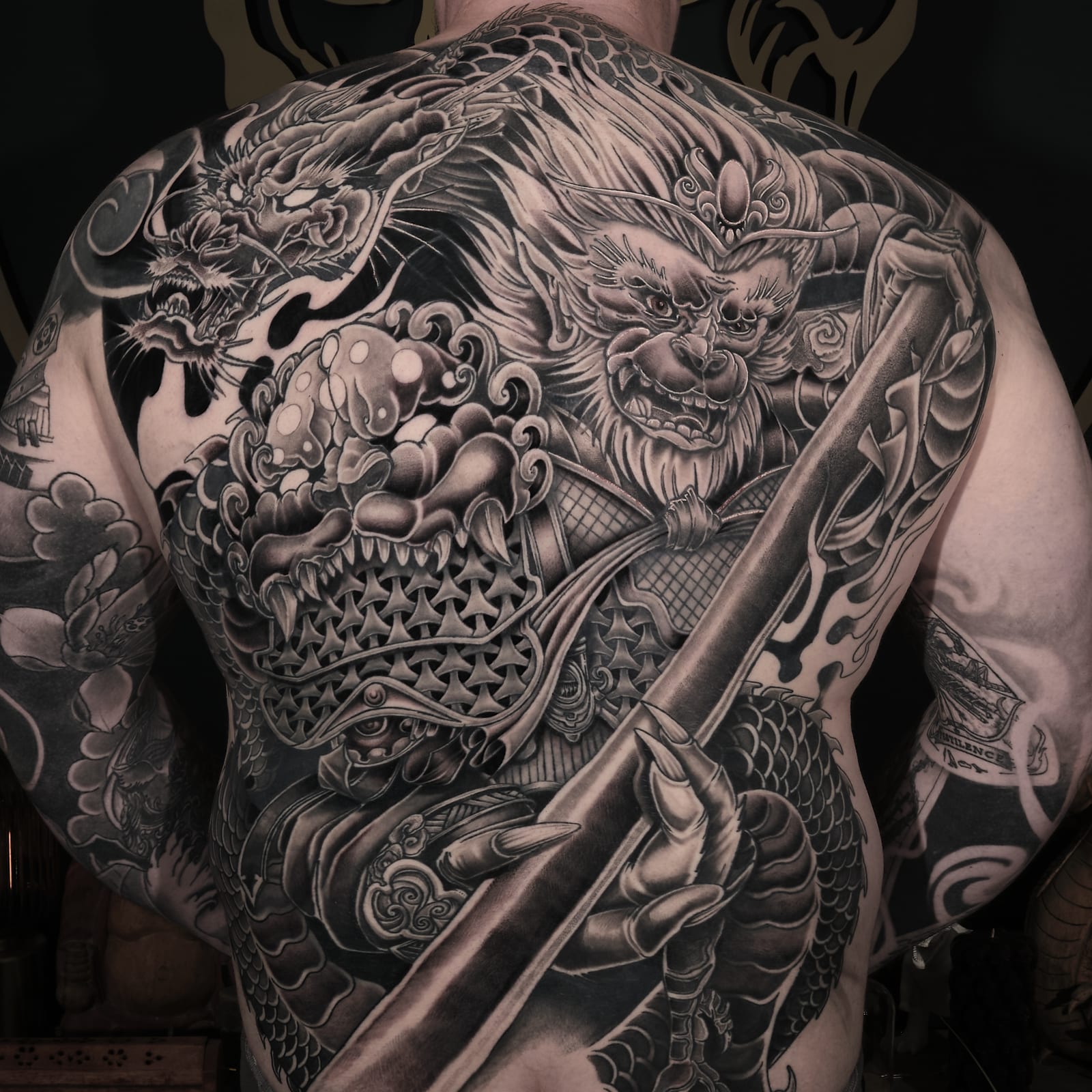 Large black and grey back tattoo of the Monkey King with a dragon and armoured warrior.