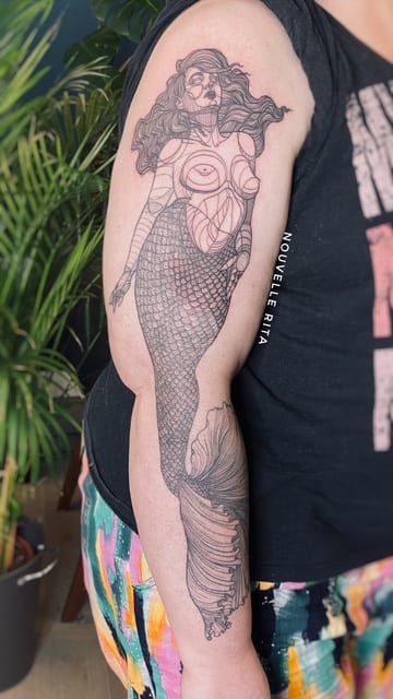 Large fine-line mermaid tattoo with detailed scales and flowing hair on an arm.