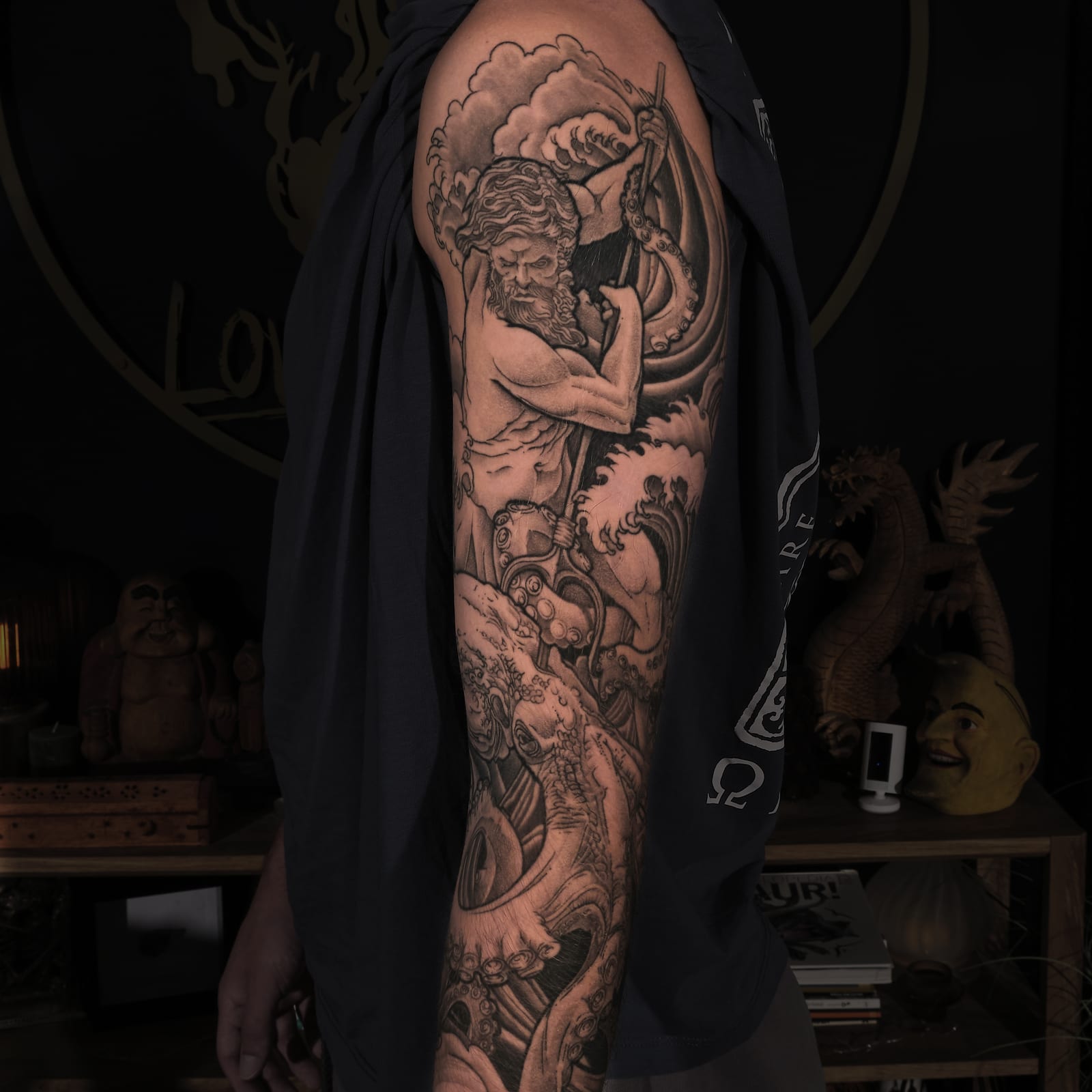 Black and grey sleeve tattoo of Poseidon with a trident, storm waves and the Kraken.